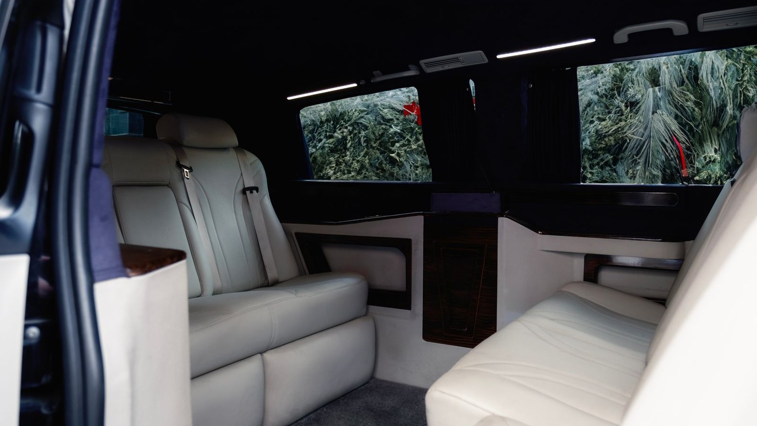 Executive van cabin with facing cream leather seating and a wood table
