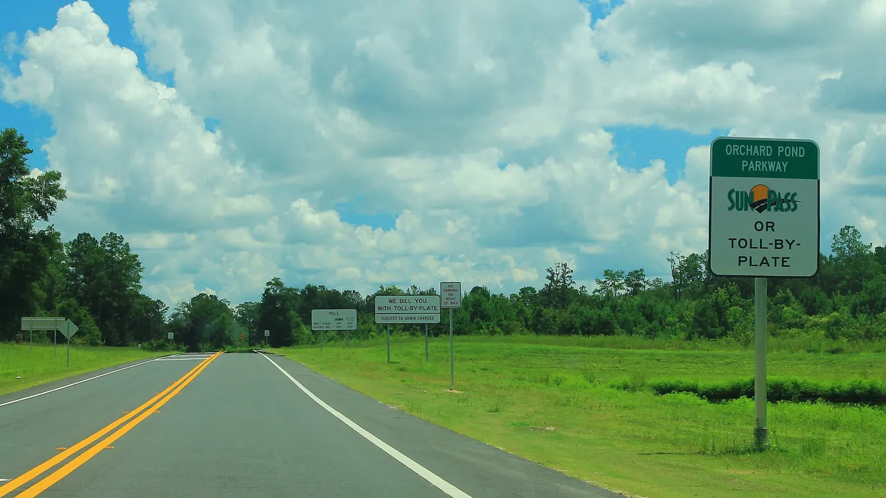 SunPass and toll-by-plate sign beside a Florida road
